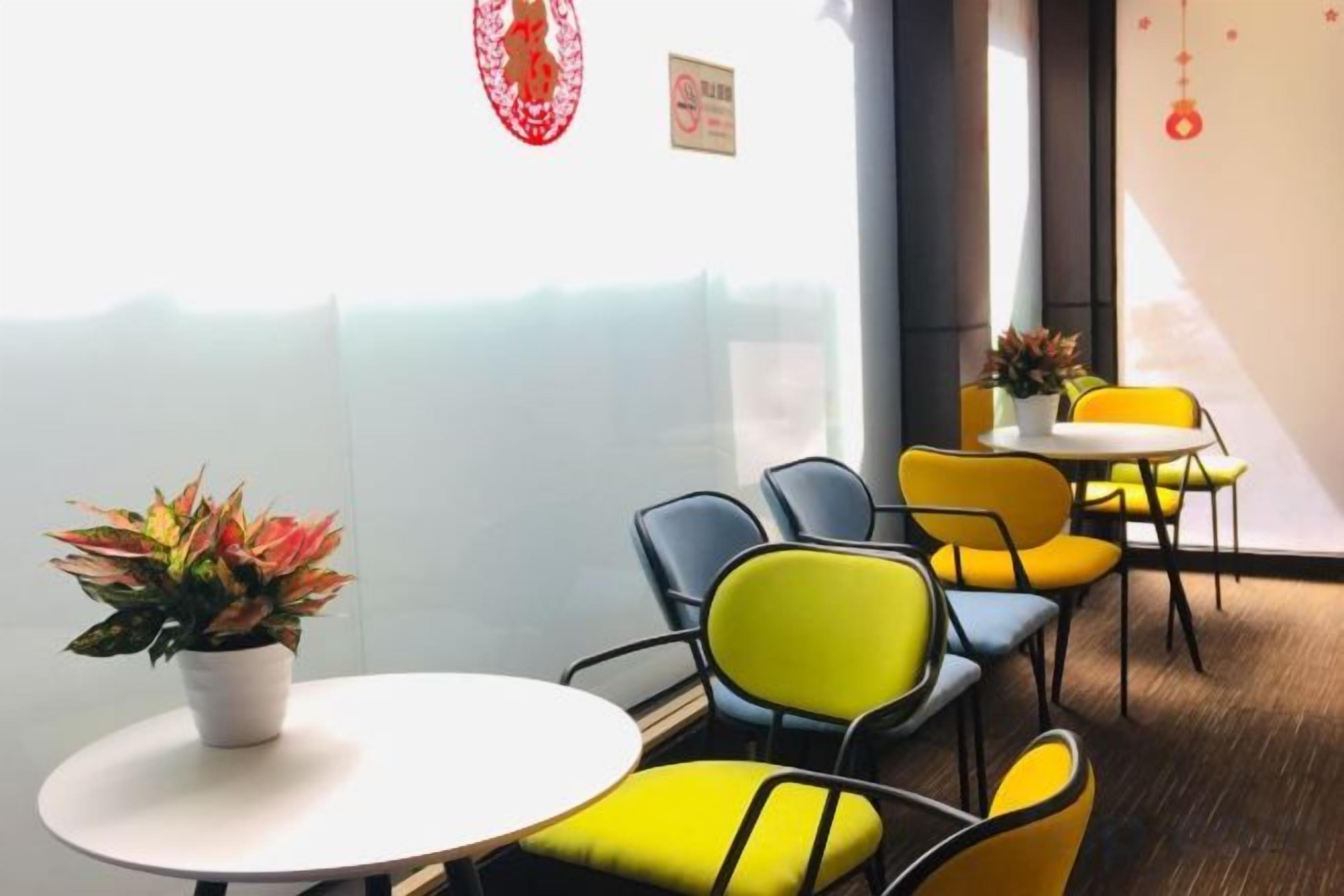 A modern interior with round tables and chairs, a potted plant, and a view through a glass partition.