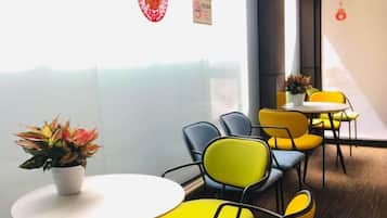 A modern interior with round tables and chairs, a potted plant, and a view through a glass partition.
