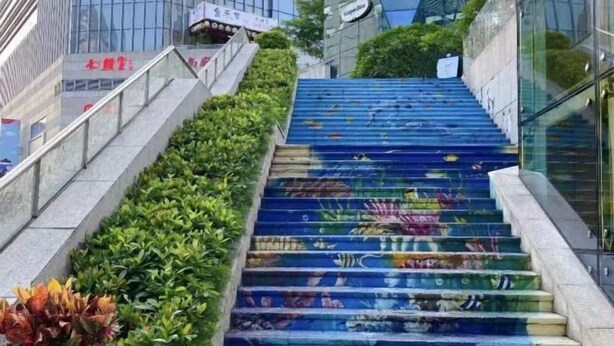 Un escalier orné de graffitis colorés, entouré de verdure et de bâtiments modernes.