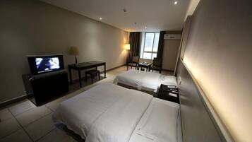 A hotel room with two beds, a TV, a desk, and a chair.