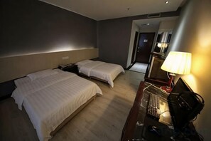 Quarto de hotel com duas camas, uma escrivaninha com abajur e uma pequena cozinha.