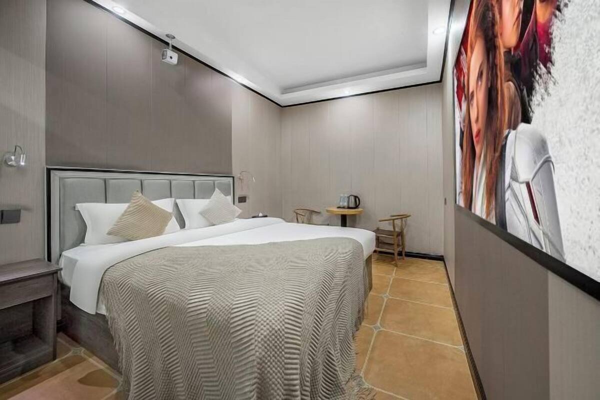 Une chambre d’hôtel moderne avec un grand lit, une petite table, une chaise et un tableau au mur.
