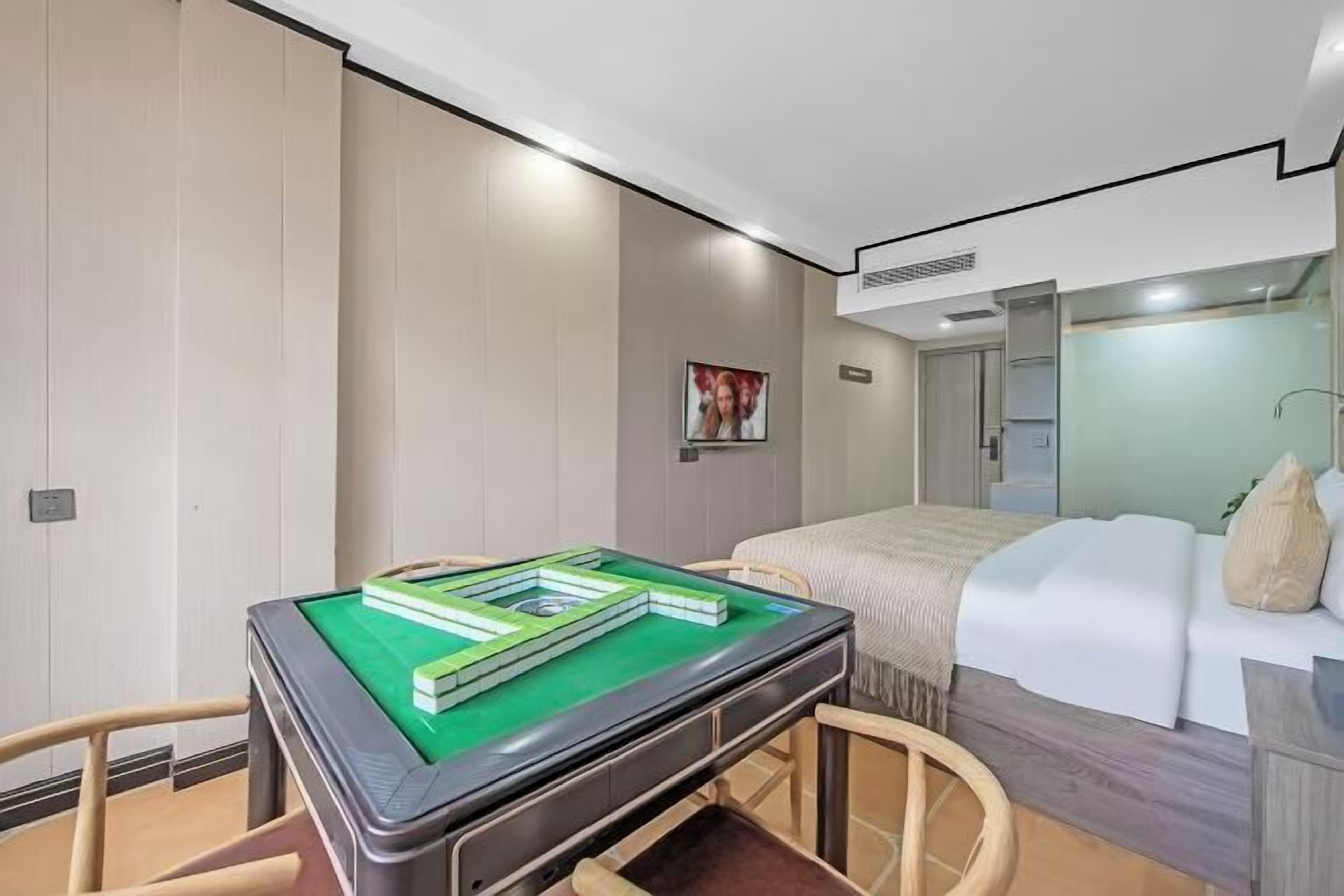 A modern hotel room with a pool table, a bed with a white headboard, and a large mirror.