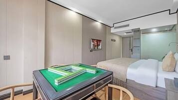 A modern hotel room with a pool table, a bed with a white headboard, and a large mirror.