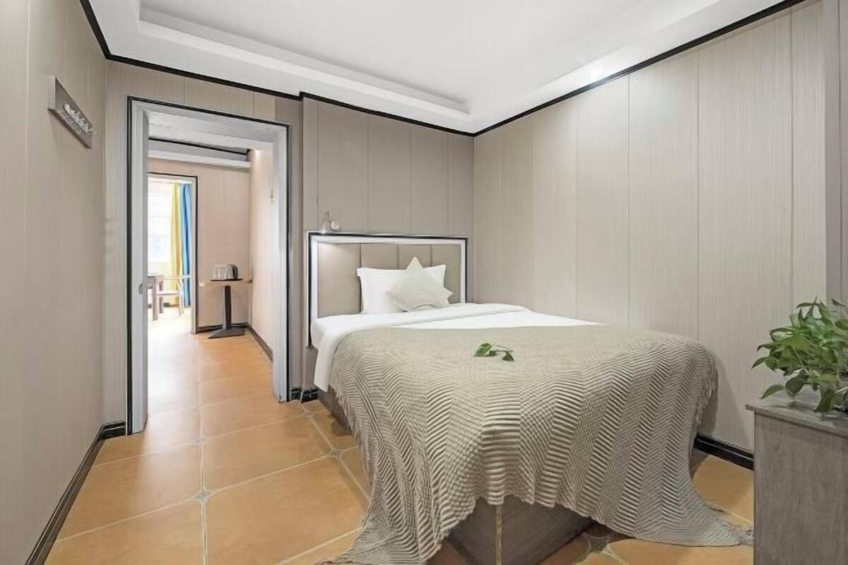 Une chambre d’hôtel avec un lit, une plante et une vue sur le couloir.
