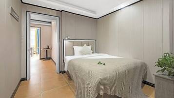 A hotel room with a bed, a plant, and a view of the hallway.