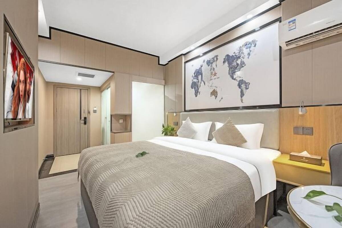 Une chambre d’hôtel avec un lit, une carte accrochée au mur, un bureau avec une chaise et une plante.