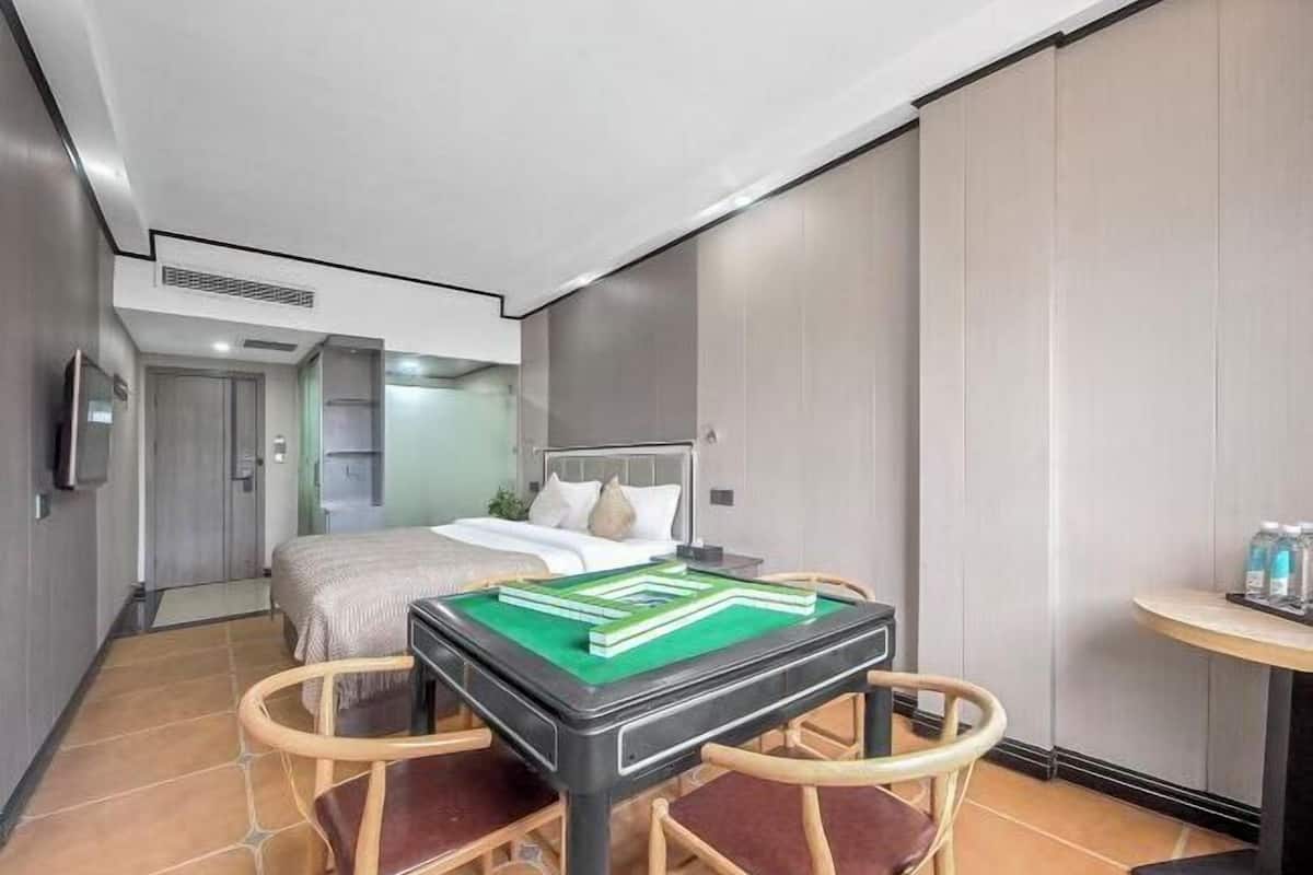 Une chambre d’hôtel avec un lit, une table recouverte d’un tapis vert et une chaise.