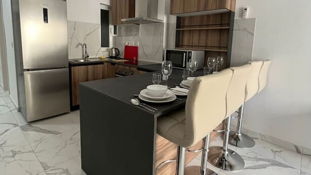 A modern kitchen with a central island, stainless steel appliances, and wooden cabinetry.