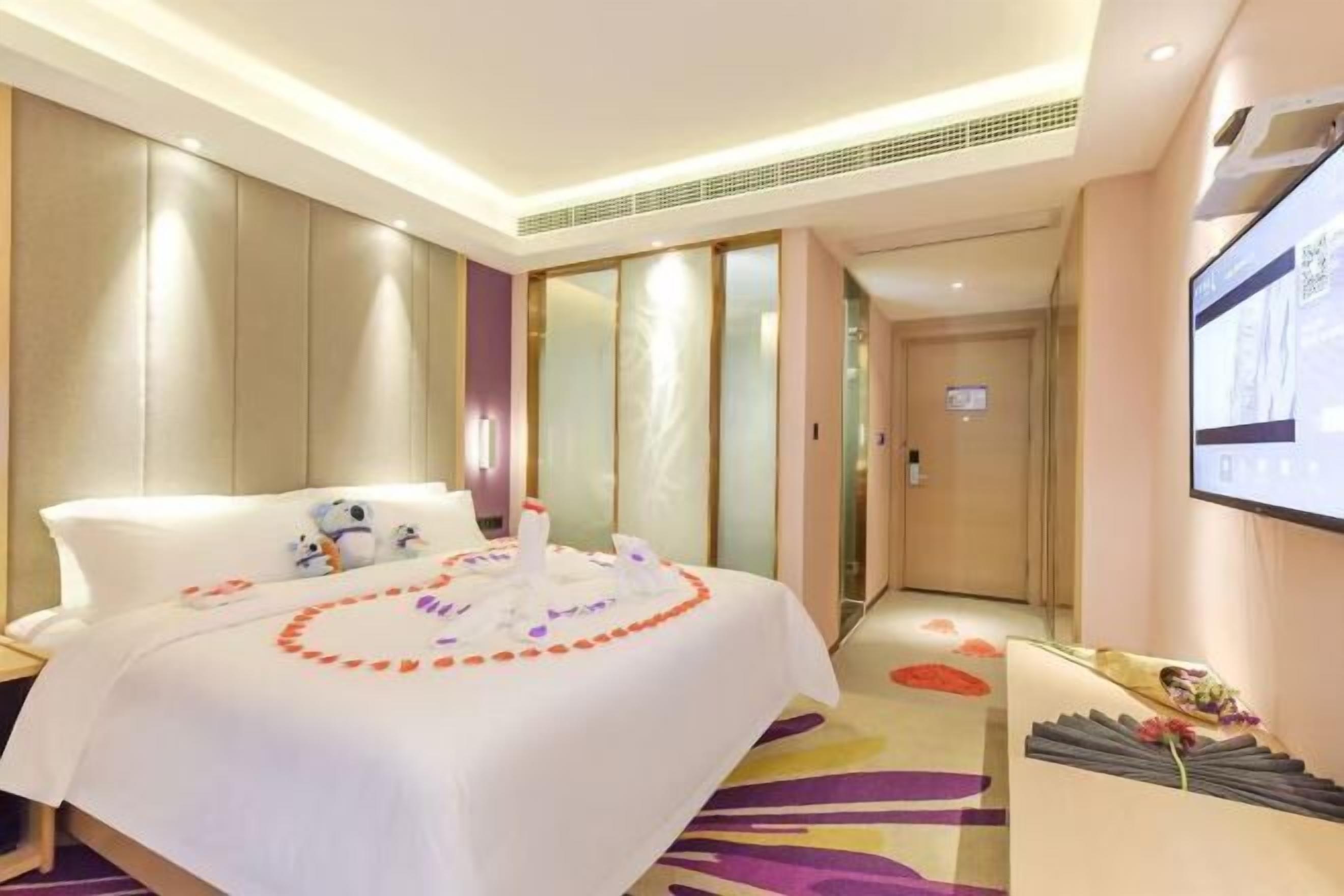 A hotel room with a bed, a TV, a desk, and a bathroom.