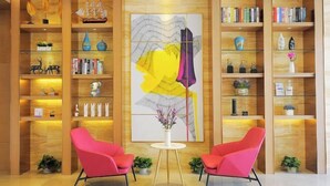 A modern lobby with wooden shelving, books, decorative items, and two pink chairs. - Lavande Hotel Guilin Railway Station Elephant Trunk Hill Scenic Area (Guilin)