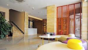 A modern lobby with a staircase, a reception desk, and a seating area with colorful cushions. - Lavande Hotel Guilin Railway Station Elephant Trunk Hill Scenic Area (Guilin)