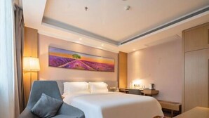 A hotel room with a large bed, a chair, a desk, and a painting on the wall. - Lavande Hotel Guilin Railway Station Elephant Trunk Hill Scenic Area (Guilin)