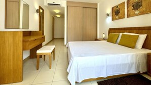 Ein Hotelzimmer mit Bett, Nachttisch, Spiegel, Kleiderschrank und Kunstwerk an der Wand.