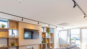 A modern living room with a grey sofa, wooden flooring, and built-in shelving with decorative items. - Decorated 2 bedroom apartment in the center (Centro Curitiba)