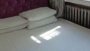 A bed with white linens and a tufted headboard. - Kailai Hotel (Mohe)