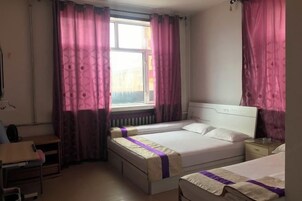 Un dormitorio con dos camas, un escritorio y una ventana con cortinas.