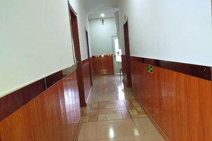 A corridor with wooden paneling and a tiled floor, leading to a door at the end.