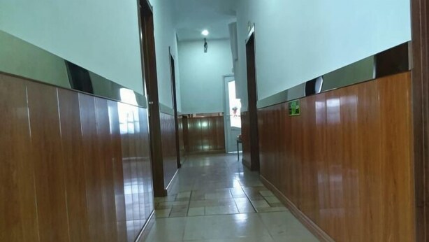 A long, narrow hallway with wooden paneling on both sides and a tiled floor. - Kailai Hotel (Mohe)