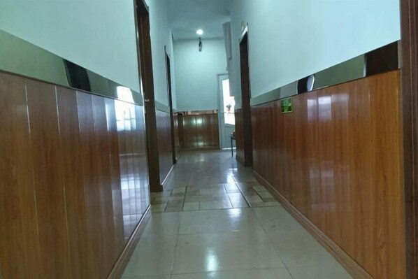 A long, narrow hallway with wooden paneling on both sides and a tiled floor. - Kailai Hotel (Mohe)
