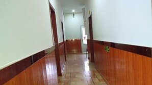 A hallway with wooden paneling and tiled flooring, leading to a door at the end. - Kailai Hotel (Mohe)