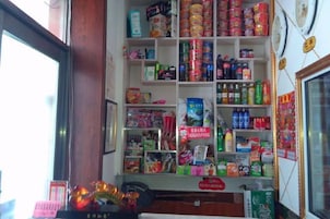 Interior de una tienda con estantes llenos de productos variados, un mostrador y una vitrina.