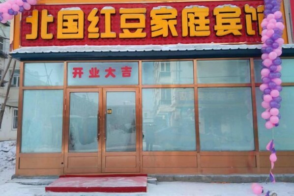 A building with a large glass facade, wooden doors, and a red awning.
