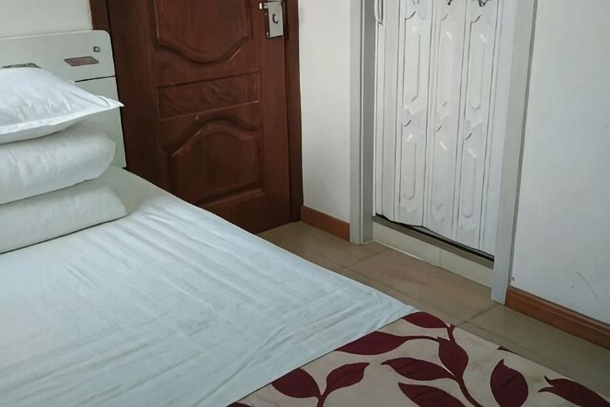 A bedroom with a bed, a wooden door, and a white wardrobe.