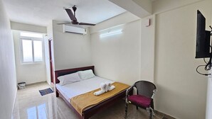 A hotel room with a bed, a chair, a ceiling fan, an air conditioning unit, a television, and a window. - L D Residency (Kilvelur)