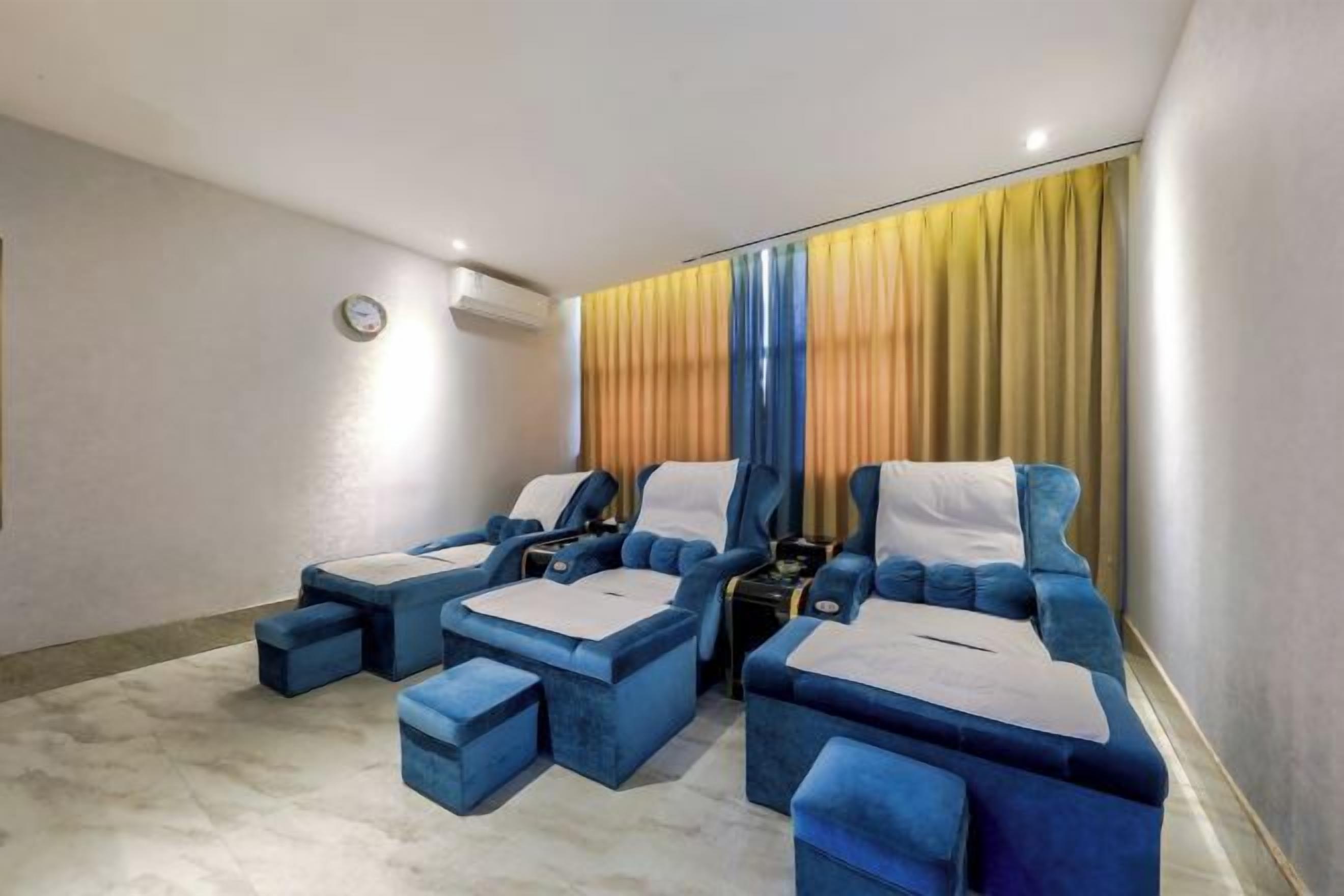 A room with two blue sofas, a small table, and a wall-mounted clock.