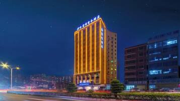 A multi-story hotel with illuminated signage, a well-maintained facade, and a parking area in the foreground.