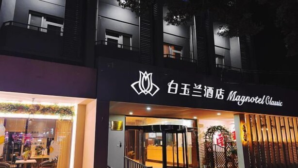 A hotel entrance with a modern design, featuring a logo and signage in a foreign language. - Magnotel Hotel (Nanchang Bayi Square People's Park Metro Station) (Nanchang)