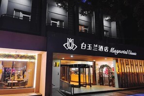 A hotel entrance with a modern design, featuring a logo and signage in a foreign language. - Magnotel Hotel (Nanchang Bayi Square People's Park Metro Station) (Nanchang)