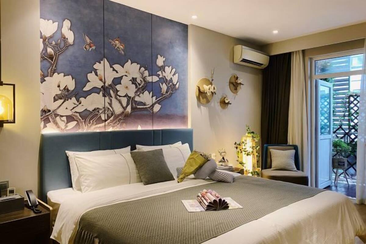 Habitación de hotel con una cama grande, aire acondicionado de pared y vistas al exterior a través de una puerta de cristal.