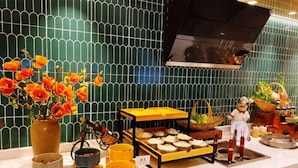 A kitchen with a tiled backsplash, a central island with food items, and a decorative figure. - Magnotel Hotel (Nanchang Bayi Square People's Park Metro Station) (Nanchang)
