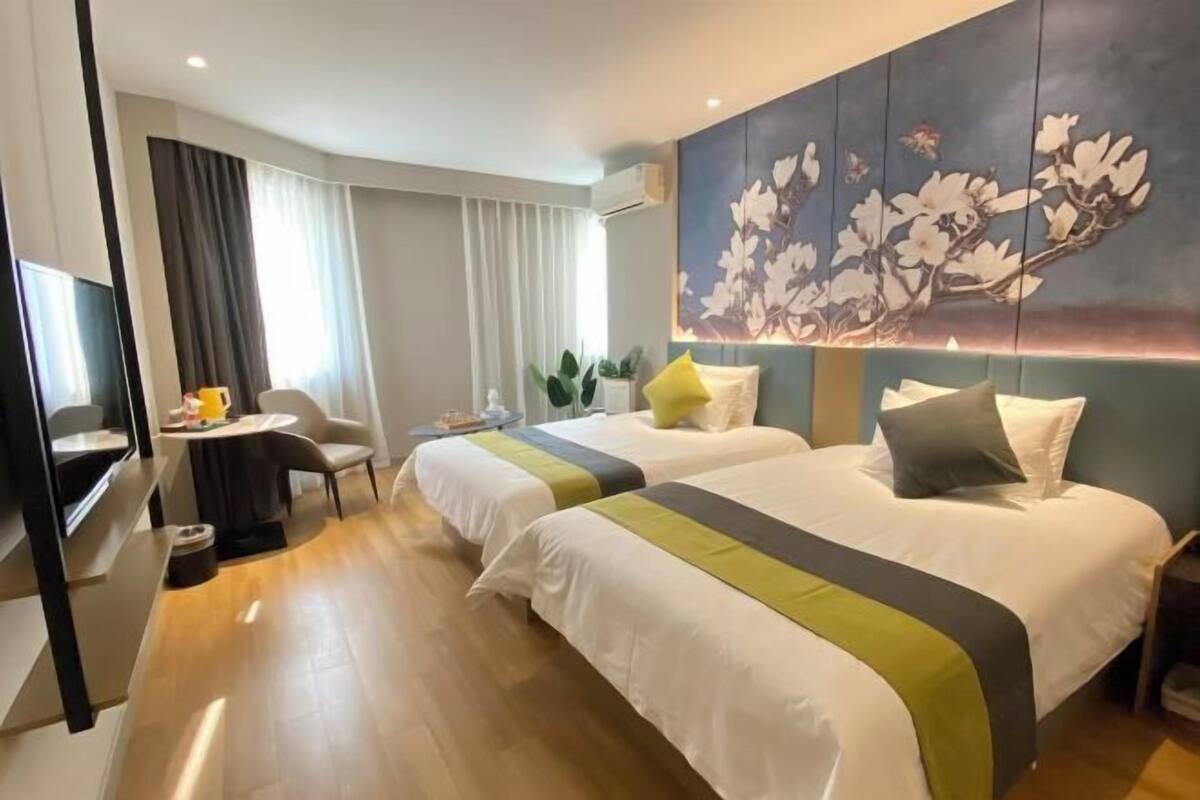 Una habitación de hotel con dos camas, un escritorio, una silla, un televisor y un cuadro en la pared.