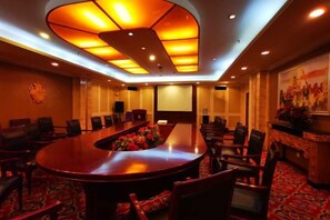Un salón de conferencias con una larga mesa, sillas y suelo alfombrado.