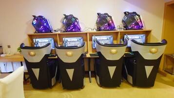 A room with four gaming chairs, each with a monitor and a gaming PC.