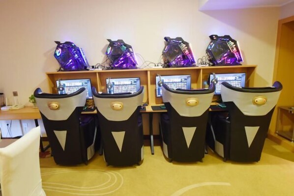 Una habitación con cuatro sillas gamer, cada una con un monitor y una computadora para juegos.