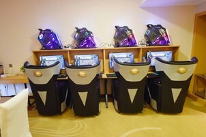 Una habitación con cuatro sillas gamer, cada una con un monitor y una computadora para juegos.