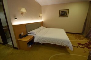 Habitación de hotel con cama, mesita de noche, lámpara y un cuadro en la pared.