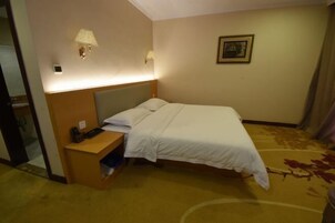 Habitación de hotel con cama, mesita de noche, lámpara y un cuadro en la pared.