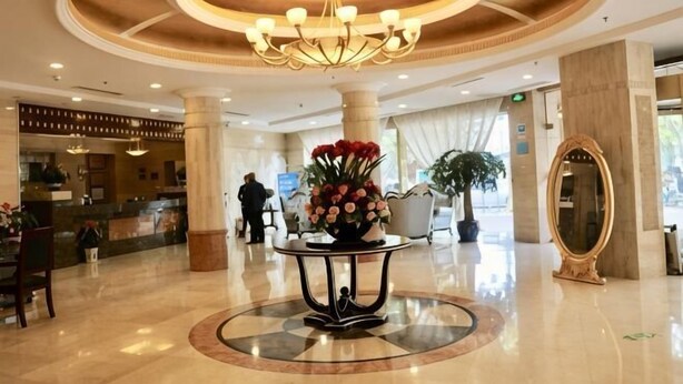 A lobby with a central round table, a chandelier, and a reception desk in the background. - Tian Zuan Wang Chao Hotel (Huai'an)