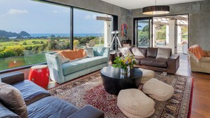 Un salón amplio con un ventanal grande que ofrece vistas panorámicas del campo y el mar.