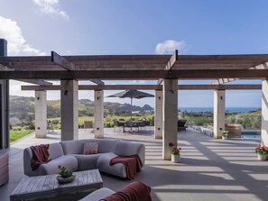 Une terrasse extérieure avec un canapé gris, une table en bois et une pergola.