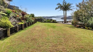 Ein gepflegter Garten mit vielfältigen Pflanzen und Blick auf das Wasser.