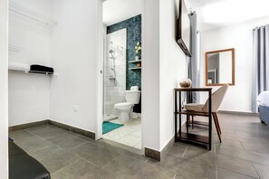 A modern bathroom with a shower, toilet, and a small table with a chair.