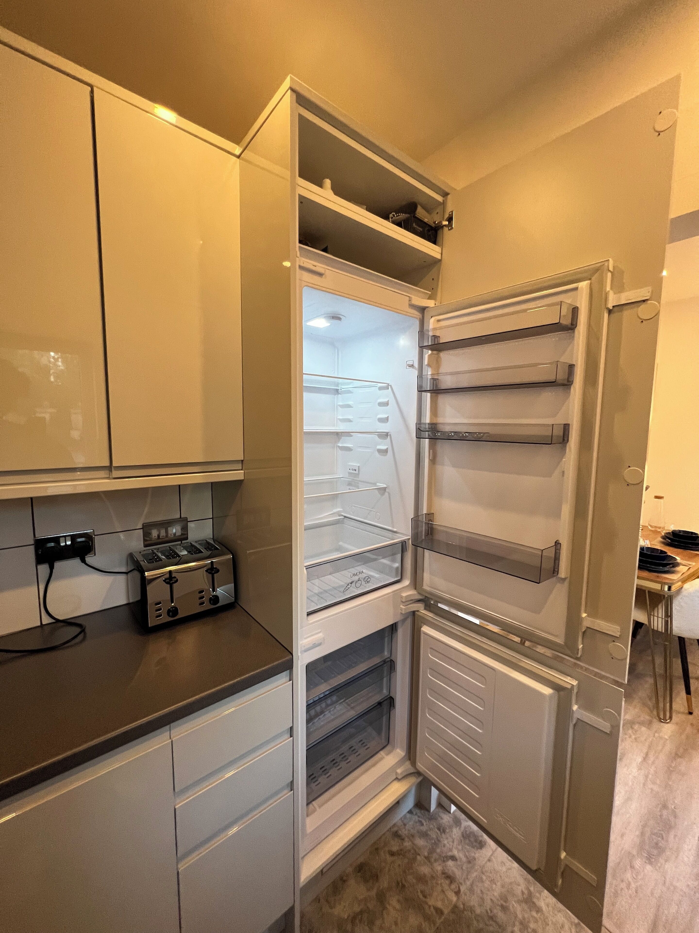 Une cuisine équipée d’un réfrigérateur encastré, d’un grille-pain et d’un plan de travail.