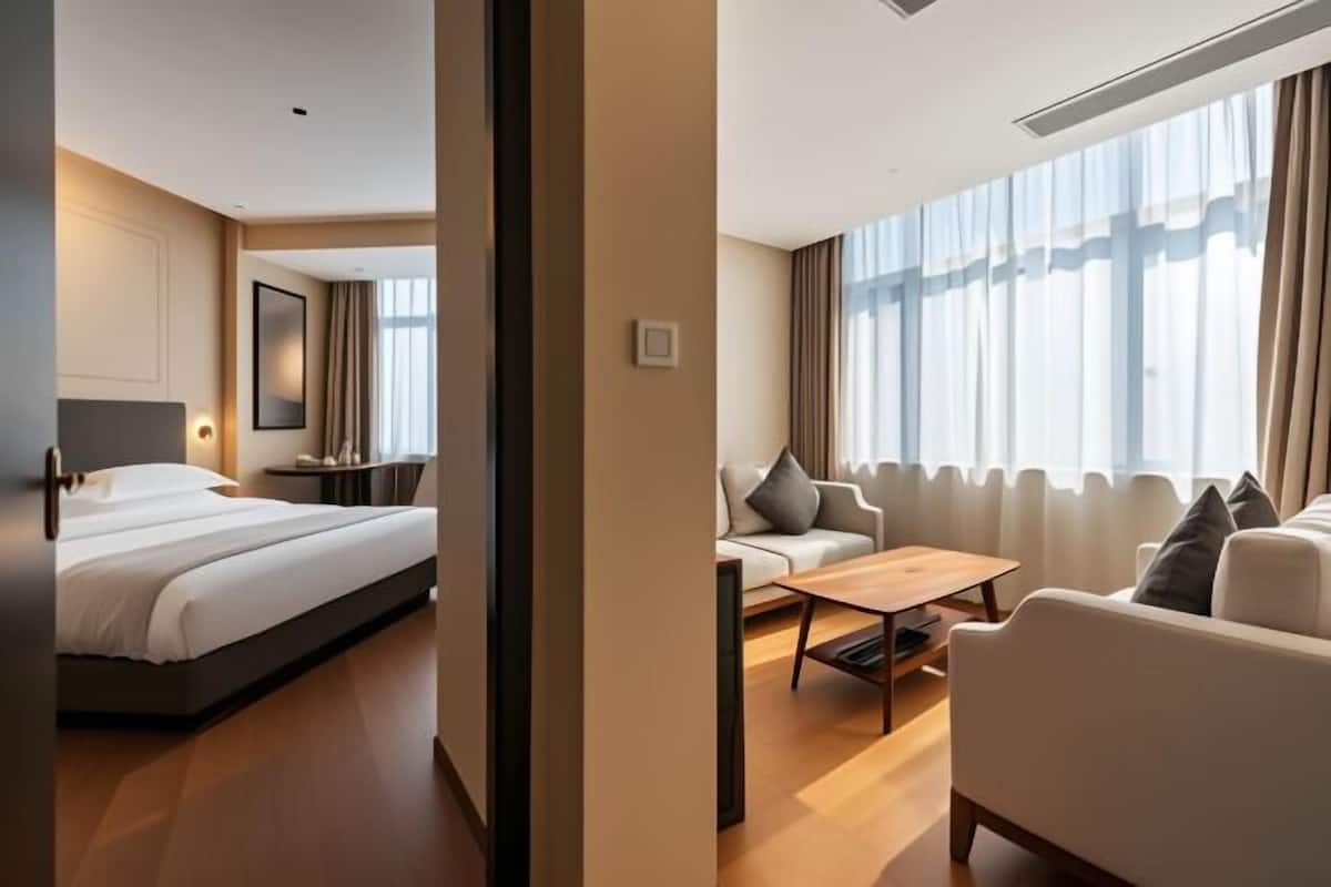 Una habitación de hotel moderna con una cama, un sofá, una mesita de centro y un gran ventanal con cortinas.