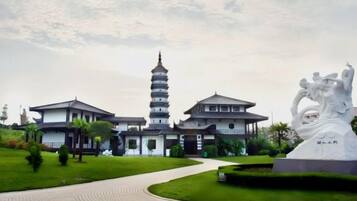 A traditional building with a pagoda-style tower, a statue, and a paved pathway.